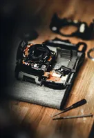 A broken and largely-disassembled black camera.